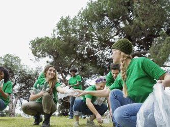 People in green shirts participate in a community clean-up outdoors.